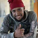 Smiling Face Adrenalin crew member in a World's Best hoodie giving a thumbs up