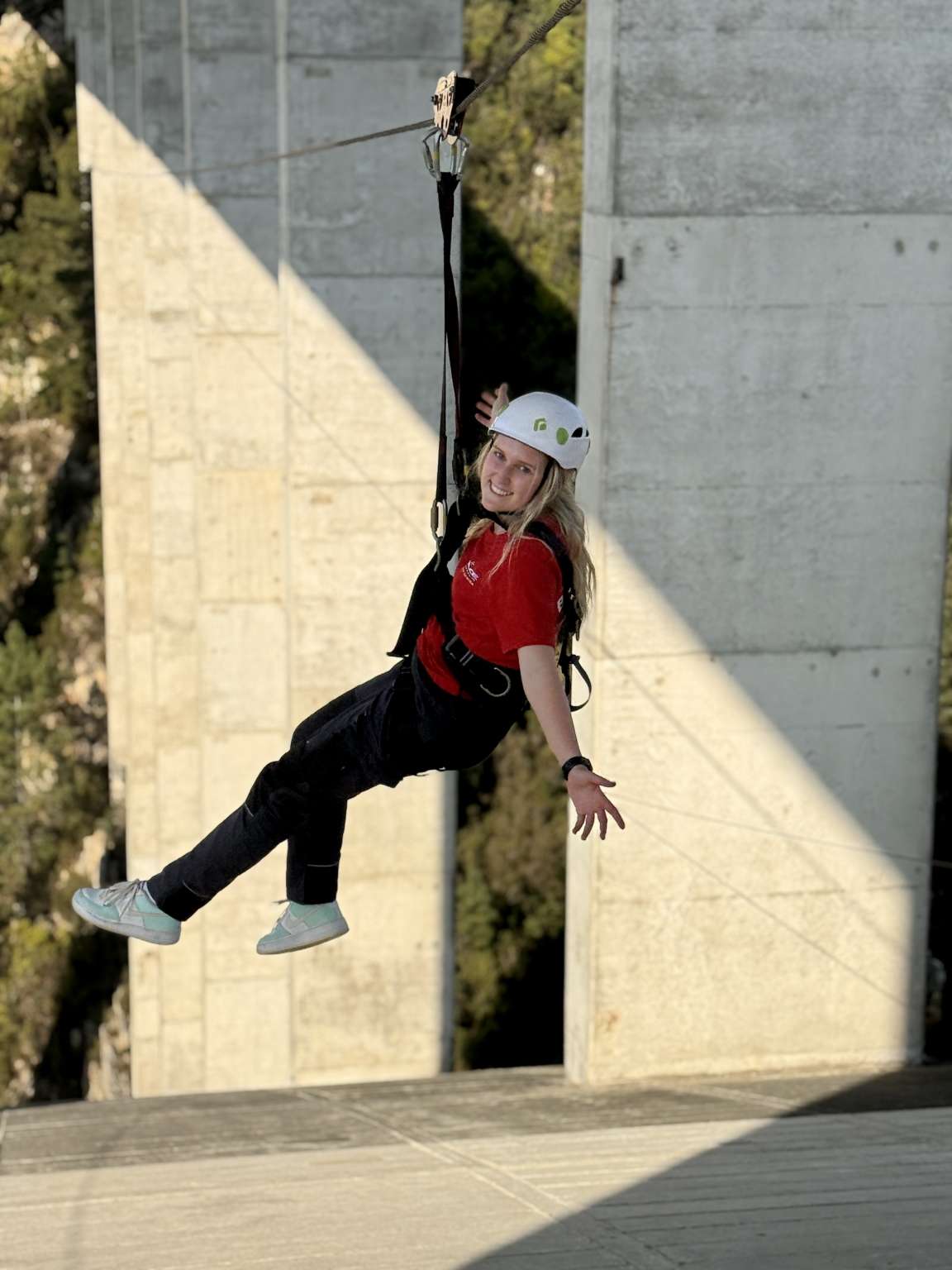 Rider on the Bloukrans zipline in a helmet and harness, passing the bridge pier