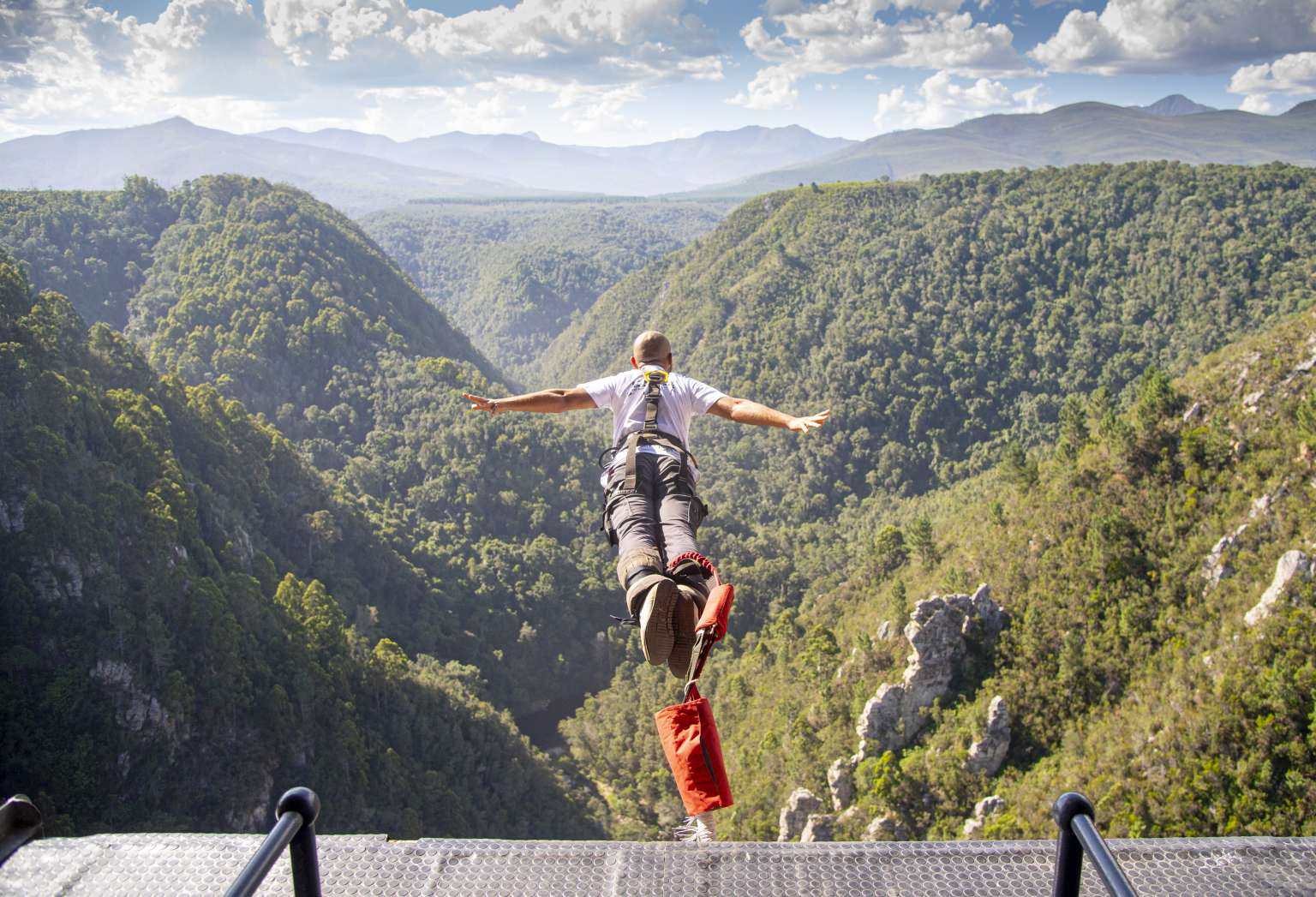 Bungy jumper in freefall with arms outstretched after leaping from Bloukrans Bridge into the gorge below