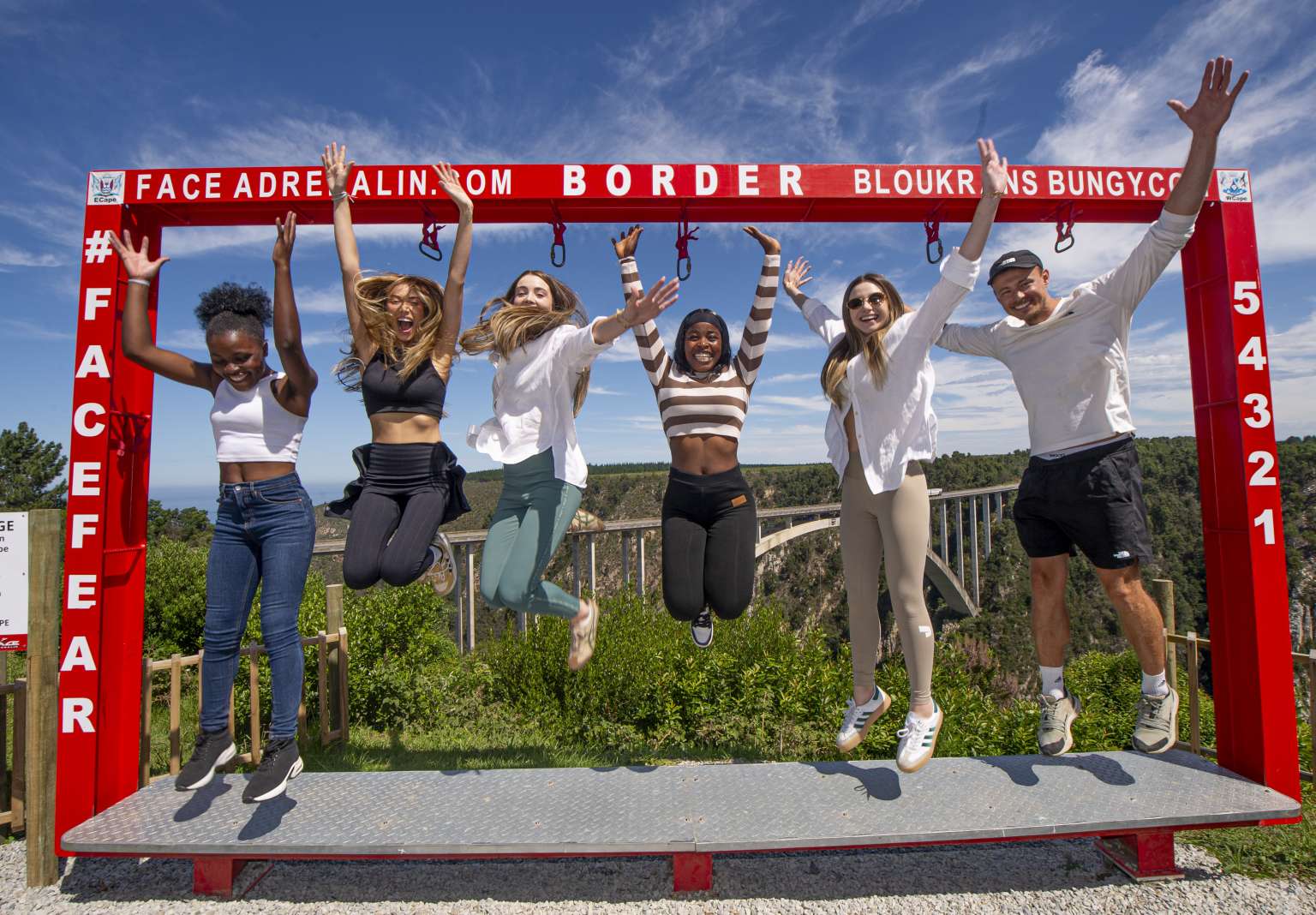 Group of visitors jumping in front of the red Face Adrenalin photo frame at Bloukrans Bridge