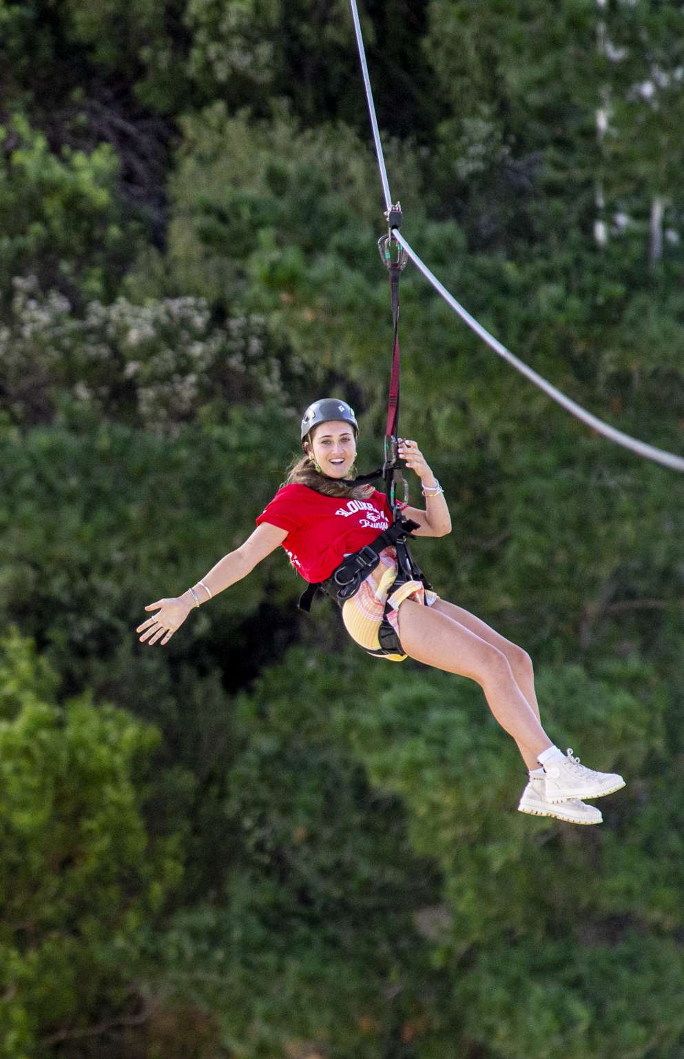 Rider on the Bloukrans zipline with the forested gorge behind