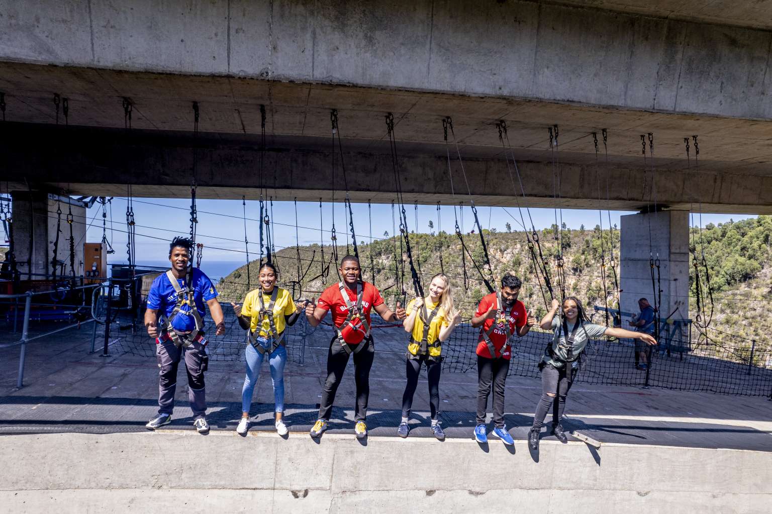 Group of visitors in harnesses lined up beneath the Bloukrans Bridge deck